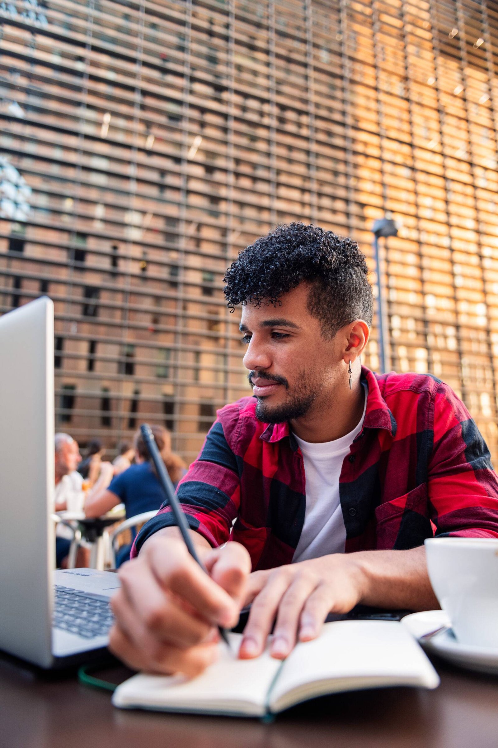 latin man studying with computer and taking notes